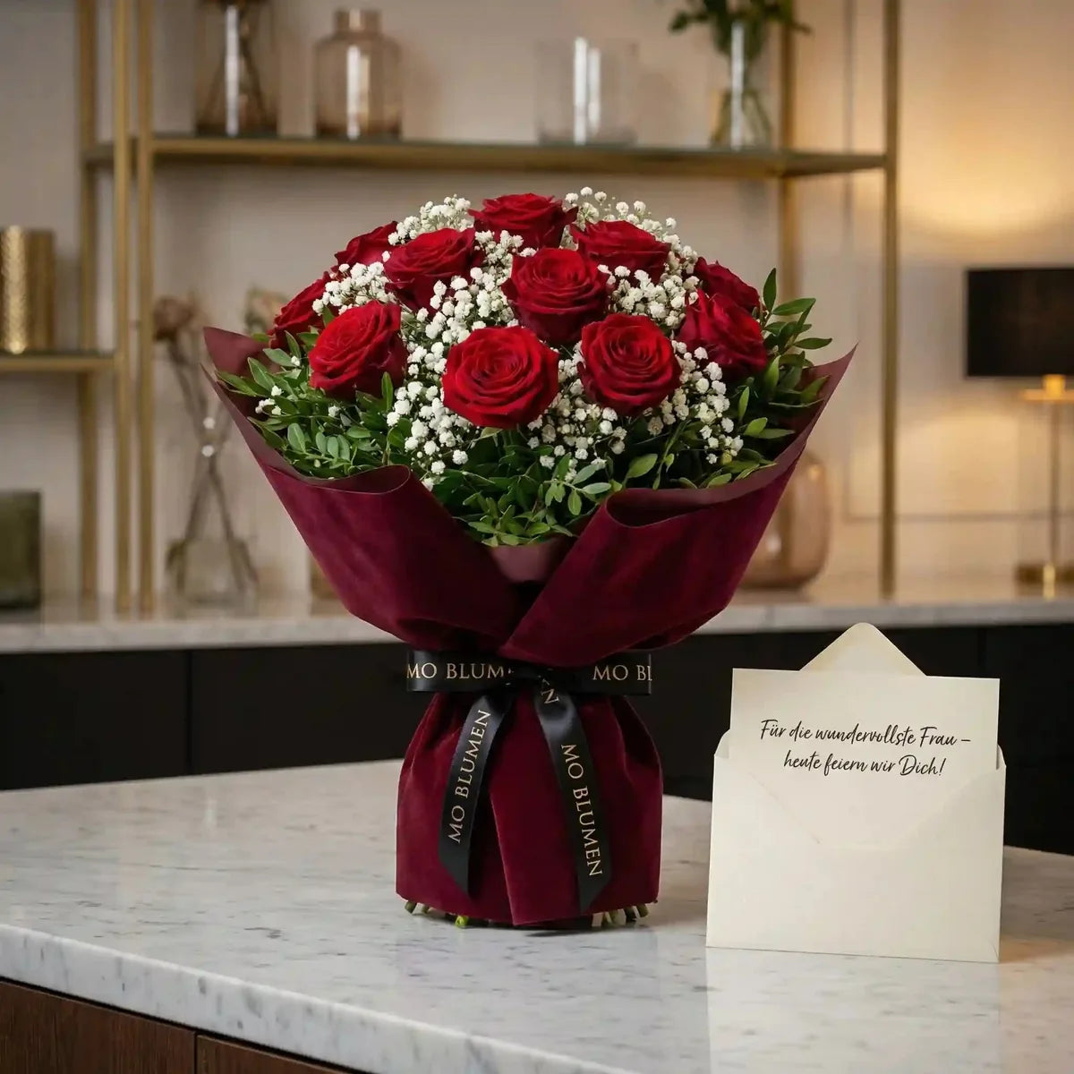 Romantischer Rosenstrauß aus roten Rosen von MO BLUMEN, in dunkelrotem Samtpapier, mit schwarzem Band und Grußkarte auf Marmor.